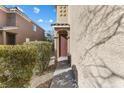 Charming entryway with a brown door, decorative archway, and manicured landscaping at 7516 Evening Melody Ct, Las Vegas, NV 89178