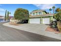 Two-story green home with three-car garage and manicured xeriscape front yard at 8908 Rocky Shore Dr, Las Vegas, NV 89117