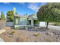 Charming green two-story home with mature landscaping, rock garden, and a well-manicured front yard at 8908 Rocky Shore Dr, Las Vegas, NV 89117