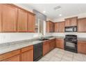 Well-lit kitchen featuring wooden cabinets, tile flooring, granite countertops, and black appliances at 10221 Mayflower Bay Ave, Las Vegas, NV 89166