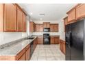 Well-lit kitchen with granite countertops, wooden cabinets, black appliances, and tile flooring at 10221 Mayflower Bay Ave, Las Vegas, NV 89166