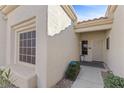 Close-up of the home's front entrance with stucco, a window, a tiled roof, and a security system sign at 2230 Spring Water Dr, Las Vegas, NV 89134