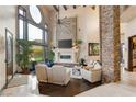 Grand living room featuring a stone fireplace, high ceilings, and large windows with a view at 5764 Aspen Falls Cir, Las Vegas, NV 89149