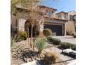 Two-story home with desert landscaping, a dark gray garage door, and a paved driveway at 10976 Bluebell Basin Rd, Las Vegas, NV 89179