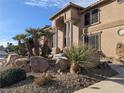 Close up shot of a tan home with unique rock and desert plant landscaping at 1534 Waterford Falls Ave, Las Vegas, NV 89123