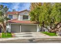 Charming two-story home featuring a tile roof, a two-car garage, and lush landscaping at 2921 Moonlight Bay Ln, Las Vegas, NV 89128