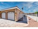 Exterior side view of home featuring a two-car garage, brick driveway and fenced-in yard at 3665 S Pointe Cir, Laughlin, NV 89029