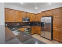 Modern kitchen featuring stainless steel appliances, dark countertops, and wooden cabinetry at 11428 Belmont Lake Dr # 104, Las Vegas, NV 89135