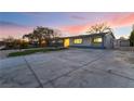 Home exterior featuring a spacious driveway leading to a detached garage, against a vibrant twilight backdrop at 616 Lacy Ln, Las Vegas, NV 89107