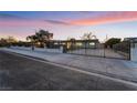 Street-level view of the property showcasing a gated entry and long driveway under a colorful twilight sky at 616 Lacy Ln, Las Vegas, NV 89107