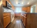 Kitchen features wood grain cabinets and island with white appliances and plenty of counter space at 7017 Green Ripple Ln, Las Vegas, NV 89156