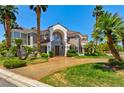 Elegant two-story home with a grand entrance, lush landscaping, mature palm trees, and a circular driveway at 3341 Camino Gardens Way, Las Vegas, NV 89146