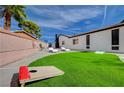 Beautiful backyard featuring a synthetic lawn, inground spa and corn hole game at 7285 Pinebrook Cir, Las Vegas, NV 89147