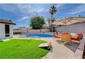 Beautiful backyard featuring a large pool, seating area, and synthetic lawn at 7285 Pinebrook Cir, Las Vegas, NV 89147
