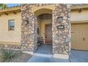 Charming stone-accented home entrance featuring a decorative wood door and cozy bench at 1049 Via Saint Lucia Pl, Henderson, NV 89011