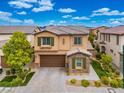 Aerial view of a tan two-story house with green shutters and a brown garage door, nicely landscaped with a brick driveway at 12240 Old Muirfield St, Las Vegas, NV 89141