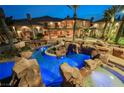 Resort-style backyard featuring a grotto-inspired pool with custom rock features and lush landscaping at 8280 Via Olivero Ave, Las Vegas, NV 89117