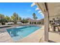 Backyard featuring a sparkling swimming pool, covered patio with seating, and lush landscaping for outdoor enjoyment at 9435 Westwind Rd, Las Vegas, NV 89139