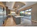 Modern kitchen featuring stainless steel appliances, a spacious island with marble countertop, and wood-look flooring at 6832 Apogee Ridge Ct, Las Vegas, NV 89135