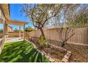 Nice backyard features include artificial turf, desert landscaping and covered patio with pergola at 7928 Broadwing Dr, North Las Vegas, NV 89084