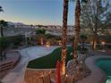 Serene backyard with a pool, artificial turf, desert landscaping, and a basketball hoop at 9012 Alpine Peaks Ave, Las Vegas, NV 89147