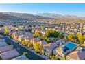 Wide aerial shot of a community with mountain views, landscaping, and varied housing at 9144 Epworth Ave, Las Vegas, NV 89148