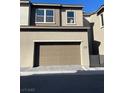 A two-car garage with a brick paver driveway in front of this two-story home at 11414 Ethereal Landing Ave, Las Vegas, NV 89138