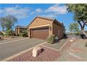 Garage of a well-maintained home with manicured landscaping, desert trees, and ample parking space at 1564 Fieldbrook St, Henderson, NV 89052