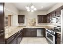 Kitchen featuring granite countertops, stainless steel appliances, dark wood cabinets, and natural light at 1851 Hillpointe Rd # 2922, Henderson, NV 89074