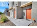 Modern townhome row featuring desert landscaping and bright orange front doors along a sidewalk at 4566 Ganier Ct # 1125, North Las Vegas, NV 89031