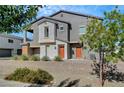 Two-story gray home featuring desert landscaping, orange doors, and a small elevated balcony at 4566 Ganier Ct # 1125, North Las Vegas, NV 89031