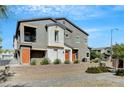 Contemporary gray two-story home featuring desert landscaping, orange doors, and a small elevated balcony at 4566 Ganier Ct # 1125, North Las Vegas, NV 89031