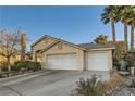 Front exterior showcasing a three-car garage, neutral paint, and beautiful landscaping with palm trees at 5022 Arizo Ct, North Las Vegas, NV 89031