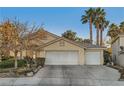 Single-story home with a three-car garage, desert landscaping, and mature palm trees under a blue sky at 5022 Arizo Ct, North Las Vegas, NV 89031