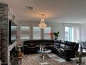 Bright living room featuring a dark leather sectional sofa and stylish crystal chandelier at 5161 Birchland Manor Ave, Las Vegas, NV 89139