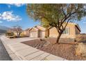 Single-story home featuring a three-car garage, desert landscaping, and sidewalks at 58 Desert Sunflower Cir, Henderson, NV 89002