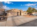 Single-story home featuring a three-car garage, desert landscaping, and blue skies at 58 Desert Sunflower Cir, Henderson, NV 89002