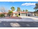 Inviting single-story home with a tile roof, desert landscaping, and mature palm trees at 60 Reyburn Dr, Henderson, NV 89074