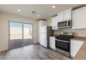 Bright kitchen featuring gray wood-look floors, white cabinets, stainless steel appliances, and a sliding glass door to the yard at 6731 Violet Cascade Ave, Las Vegas, NV 89156