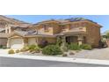 Inviting two-story home showcasing a xeriscaped front yard, three-car garage, and solar panels on a tile roof at 764 Canary Wharf Dr, Las Vegas, NV 89178