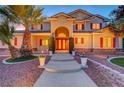 Stunning home with an arched entryway, red shutters, a lush palm tree and manicured landscaping at 7771 Pleasant Slopes Ct, Las Vegas, NV 89131