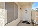 Covered front porch featuring a white front door adorned with a festive wreath and a welcoming bench at 2129 Sun Swept Way, Henderson, NV 89074