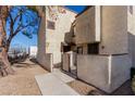 Two-story stucco exterior of a townhouse with a fenced front patio and mature tree at 5015 Spencer St # C, Las Vegas, NV 89119