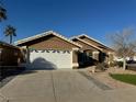 A well-maintained single-story home with a two-car garage and desert landscaping under a clear sky at 70 Moonlight Village Ln, Henderson, NV 89012