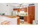Functional kitchen featuring light appliances, warm wood cabinets, breakfast bar and ceiling fan at 1381 E University Ave # 301, Las Vegas, NV 89119