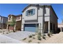 Side view of a two-story house with gray exterior, a blue garage door, and landscaped yard at 5269 Acadia Leaf St, Las Vegas, NV 89166