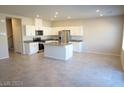 A spacious kitchen with a granite island, stainless steel appliances, and white cabinets at 5269 Acadia Leaf St, Las Vegas, NV 89166