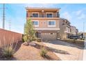 A three-story home features a balcony and a two-car garage, as well as desert landscaping at 5565 Dreaming Tree St, Las Vegas, NV 89141