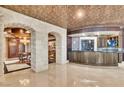 Entertaining bar area with stone archways, custom cabinets, and unique ceiling details at 9103 Alta Dr # 1502, Las Vegas, NV 89145