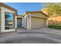 Welcoming single-story home featuring stone accents, mature landscaping, and a paver driveway to the two-car garage at 9765 Skye Star Ave, Las Vegas, NV 89166